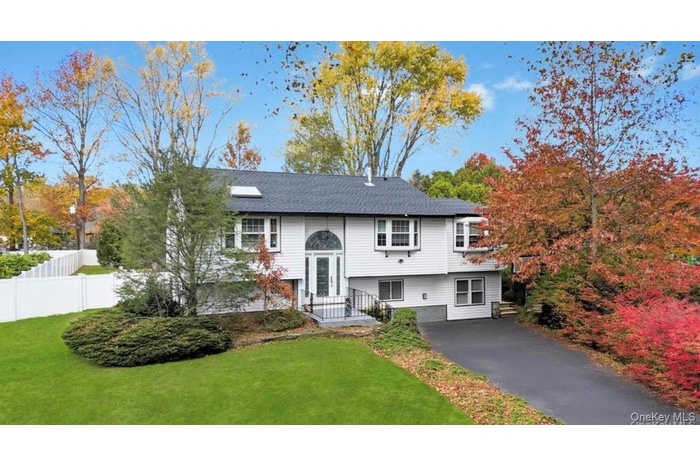 Raised ranch featuring roof with shingles and driveway