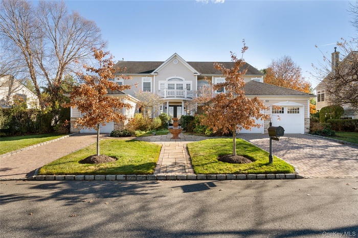 View of front of property with a balcony, french doors, a front yard, decorative driveway, and stone siding