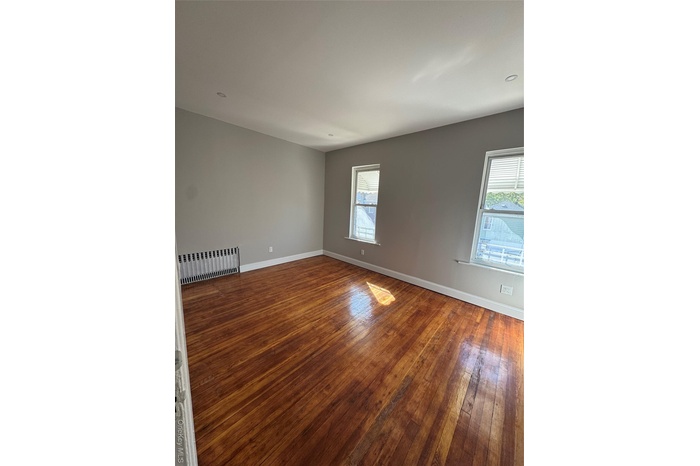 Unfurnished room with radiator heating unit and dark wood-type flooring