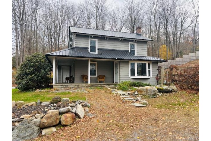 View of front facade featuring a metal roof, covered porch, and a chimney