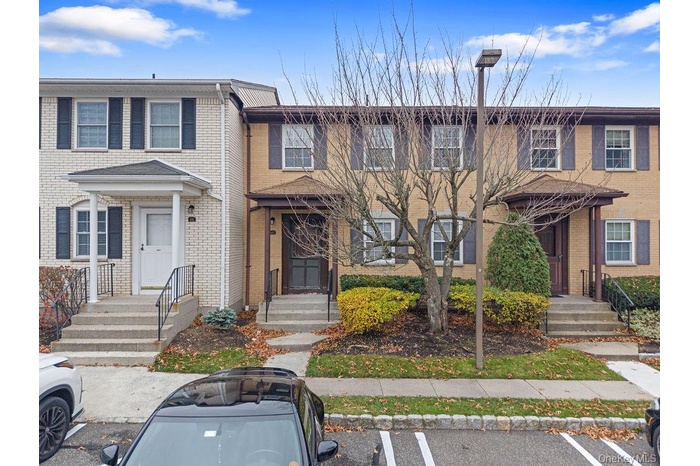 View of front facade featuring uncovered parking and brick siding