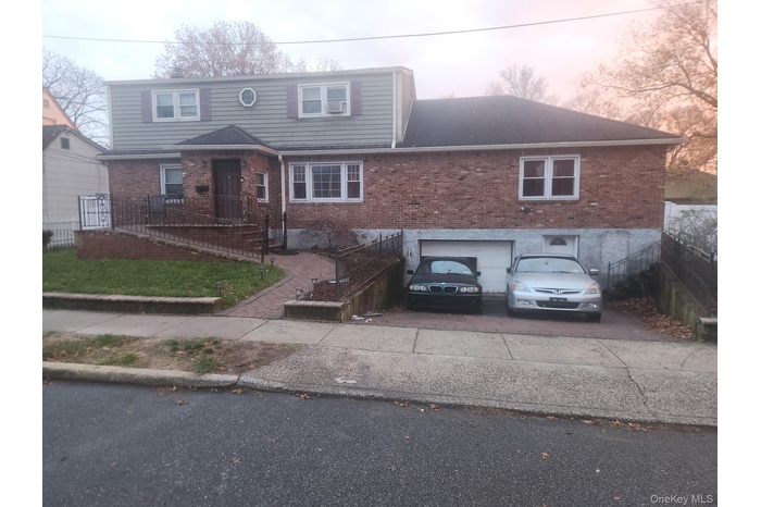 View of front of property with brick siding, a garage, and driveway