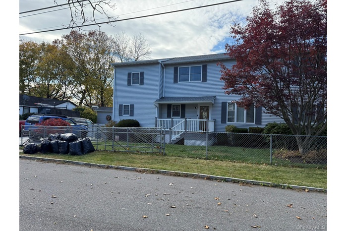 Traditional-style house featuring a porch and a fenced front yard