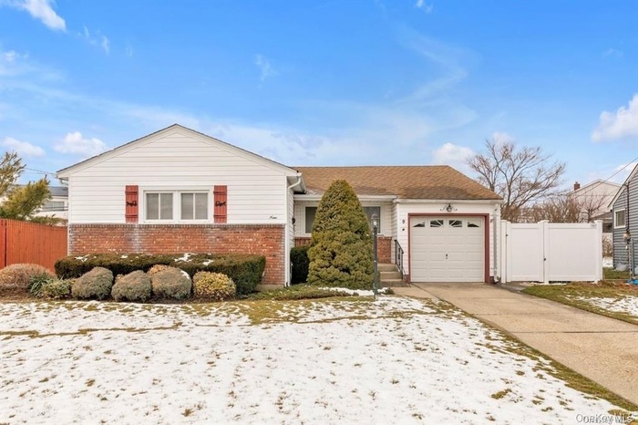 View of front facade with brick siding, a garage, driveway, and a gate