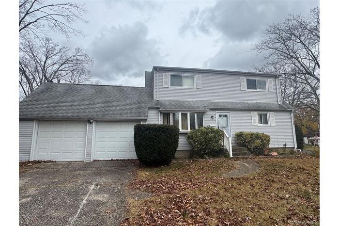Traditional home with driveway, an attached garage, and a shingled roof