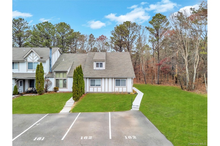 View of front of property featuring a shingled roof, a front yard, and uncovered parking