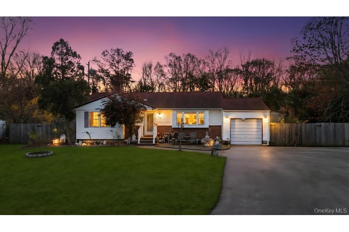 Single story home featuring asphalt driveway, an attached garage, brick siding, and an outdoor fire pit