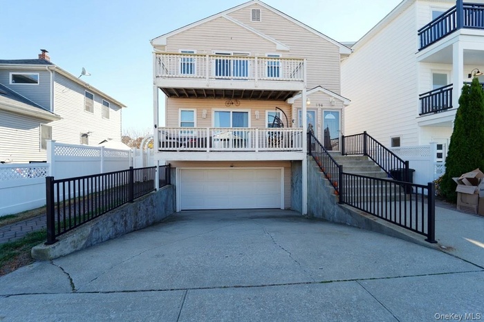 View of front of house with driveway, a garage, and a balcony