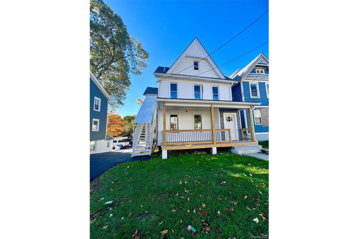 View of front of home with a front lawn, stairway, and covered porch
