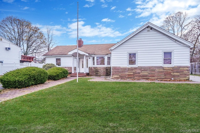 View of front facade featuring stone siding, a chimney, a shingled roof, and entry steps