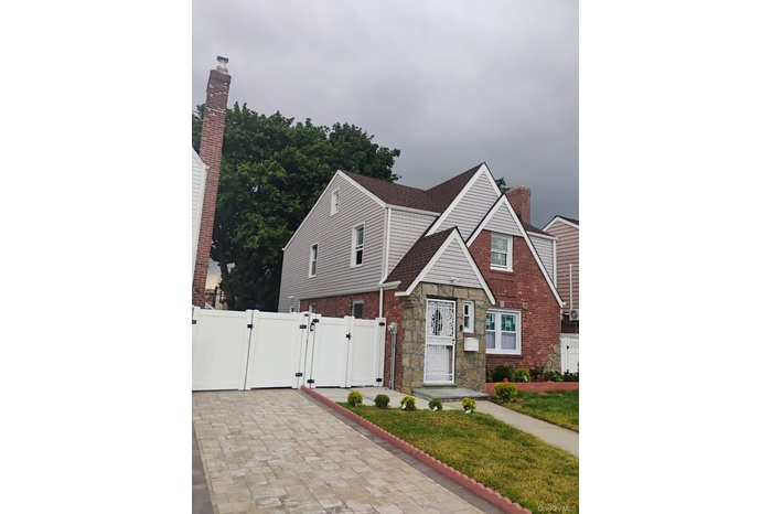 View of front of house featuring a gate, stone siding, and a chimney
