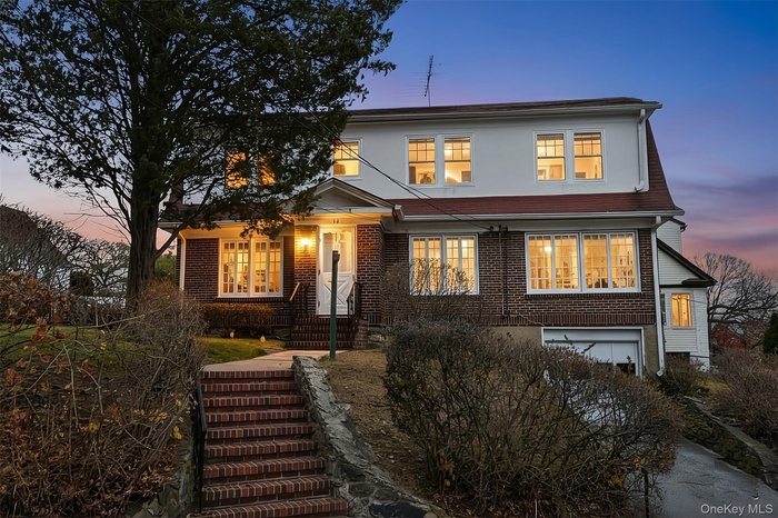 View of front of house with a garage, brick siding, and stucco siding