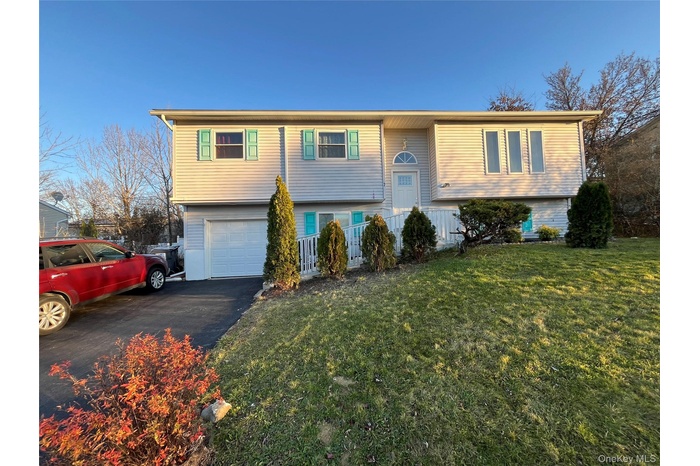 Split foyer home with asphalt driveway, an attached garage, and a front lawn