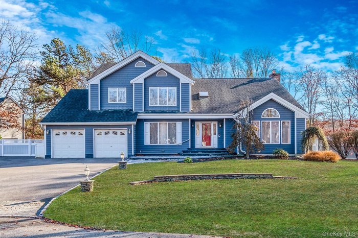View of front facade with asphalt driveway, a shingled roof, and a chimney