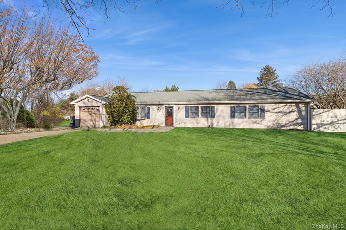 Ranch-style house featuring a front lawn, driveway, and an attached garage