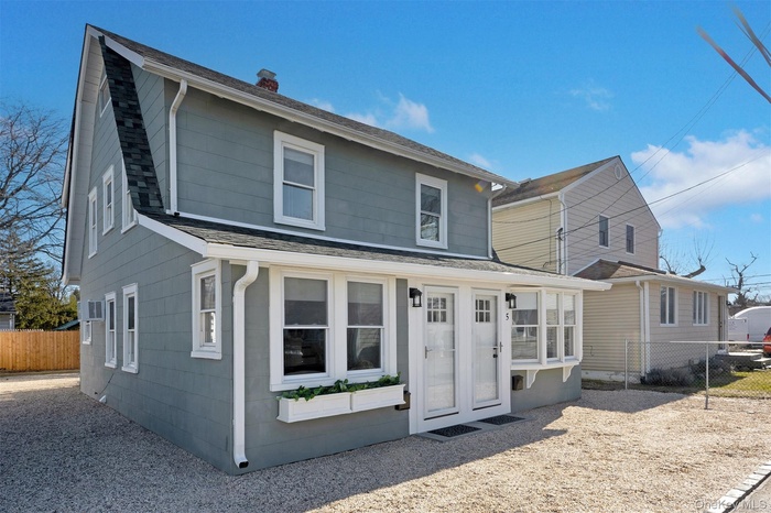 View of front of property featuring a chimney, a wall mounted AC, and a shingled roof