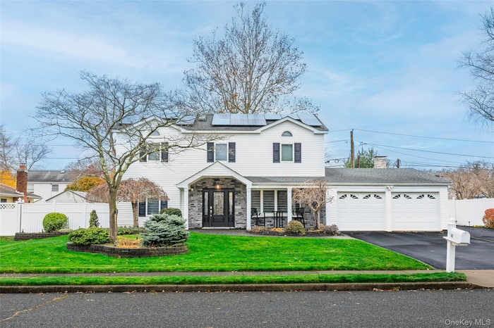 Traditional-style home featuring an attached garage, solar panels, asphalt driveway, french doors, and covered porch