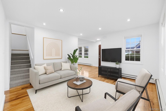 Living room with baseboard heating, recessed lighting, stairway, and light wood-style floors