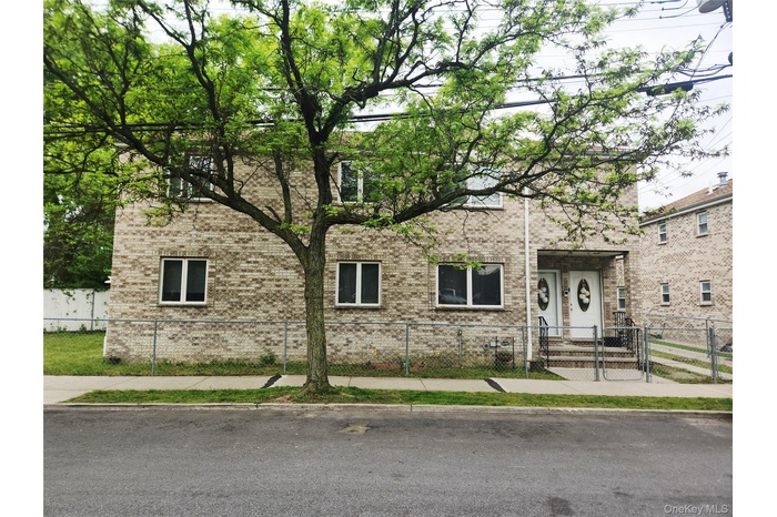 View of front of house with brick siding, a fenced front yard, and a gate