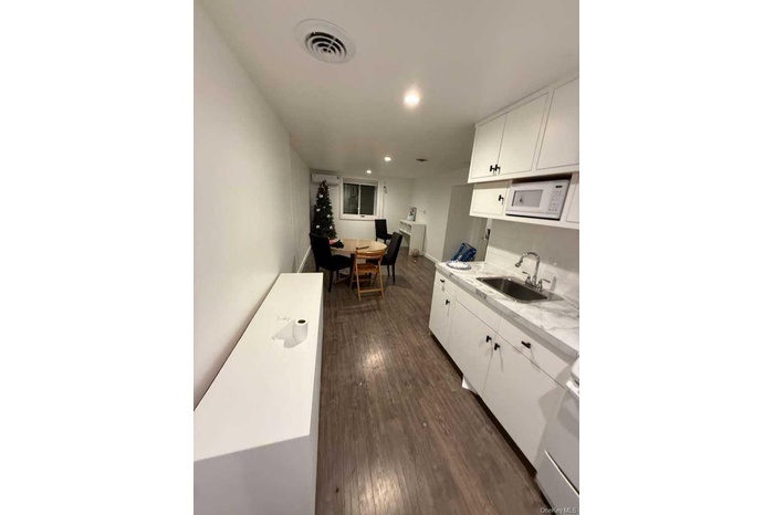 Kitchen with white cabinetry, dark wood-style floors, white appliances, and recessed lighting
