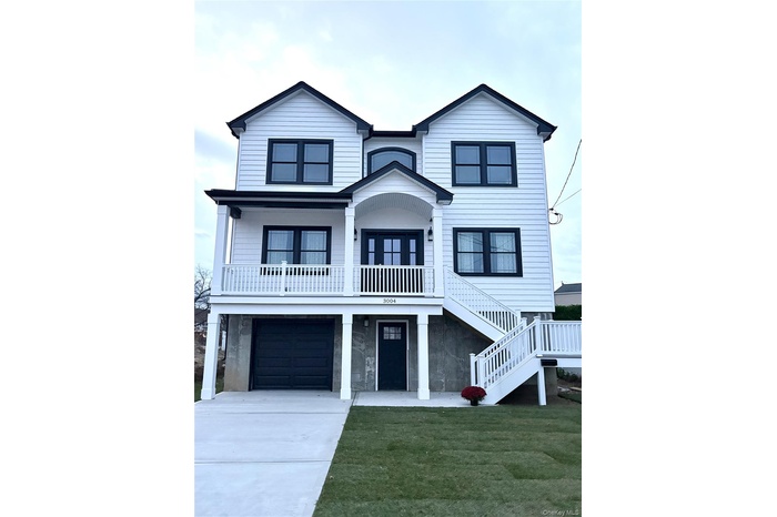View of front of house featuring a front yard, stairway, concrete driveway, an attached garage, and covered porch