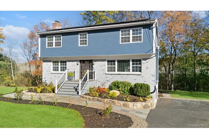 Colonial home featuring a front yard, brick siding, and a chimney