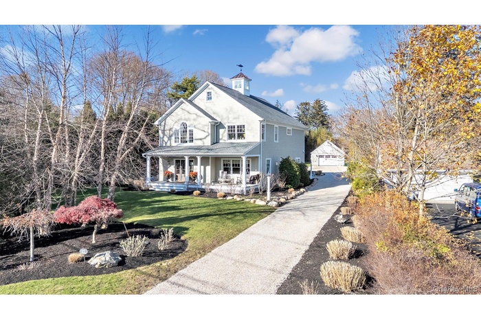View of front of property featuring covered porch, a front yard, concrete driveway, a garage, and an outdoor structure