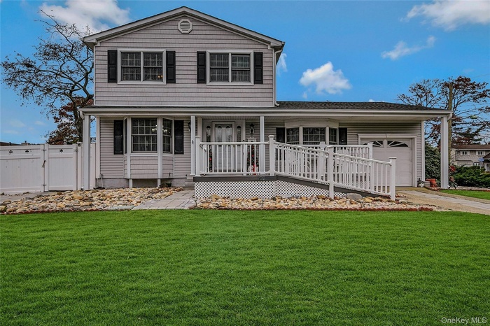 Traditional-style home with a gate, an attached garage, driveway, a porch, and a shingled roof