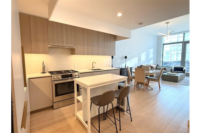 Kitchen featuring light countertops, stainless steel range with gas stovetop, modern cabinets, and a wall of windows