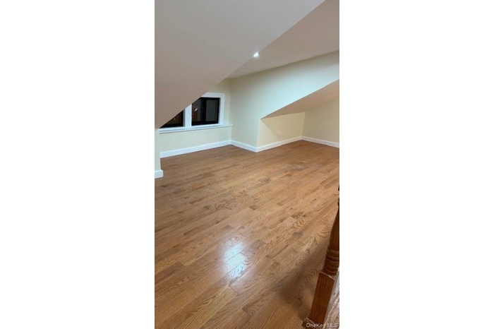 Additional living space with light wood-style floors and lofted ceiling