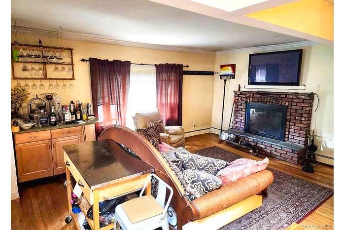 Living room featuring dark wood finished floors, a fireplace, and ornamental molding