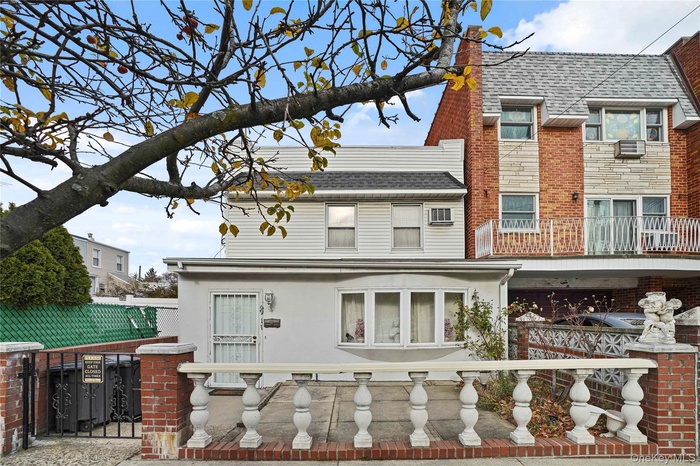 Back of property featuring a fenced front yard, a shingled roof, stucco siding, and a balcony