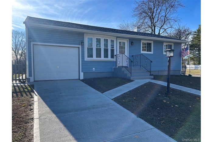 Ranch-style home with concrete driveway, a chimney, and a garage