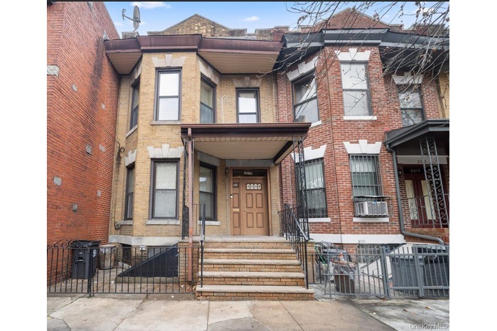 View of front of property featuring brick siding, a fenced front yard, a gate, and cooling unit