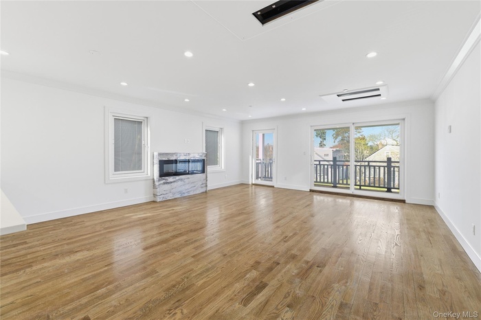 Unfurnished living room featuring light wood-style floors, a premium fireplace, crown molding, and recessed lighting