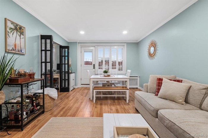 Living area featuring light wood-style flooring, recessed lighting, ornamental molding, and radiator