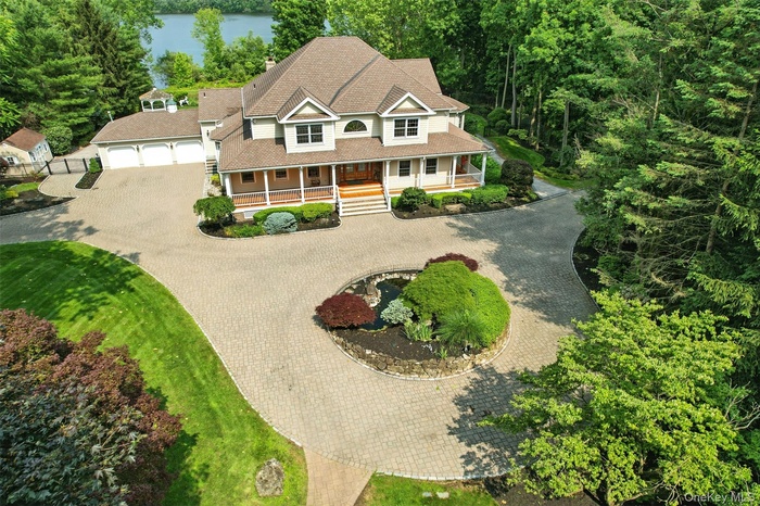 View of front of home with curved driveway, a porch, and a water view
