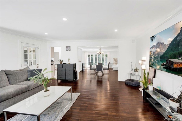 Living area with wood finished floors, ornamental molding, a chandelier, and recessed lighting