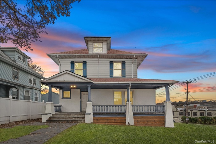 Traditional style home featuring a yard, a porch, and a shingled roof