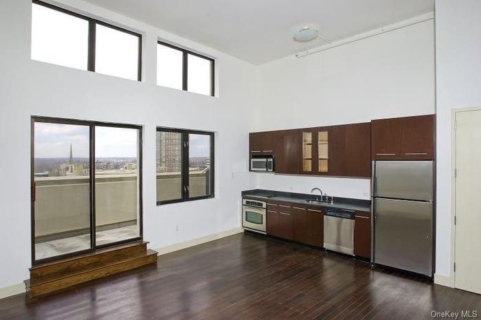 Kitchen with dark countertops, dark brown cabinetry, a high ceiling, stainless steel appliances, and dark wood-style flooring