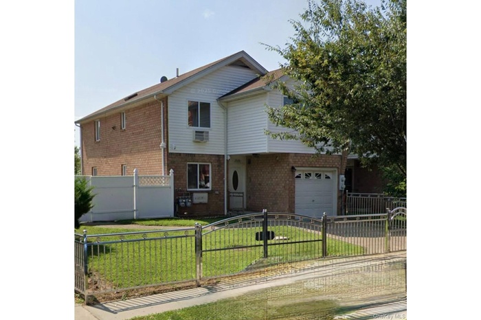 View of front of house with a fenced front yard, brick siding, a garage, and a gate