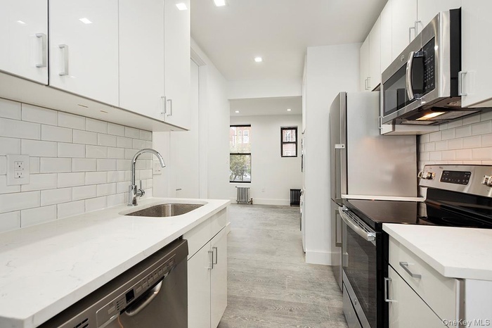 Kitchen with stainless steel appliances, tasteful backsplash, white cabinets, light wood finished floors, and recessed lighting