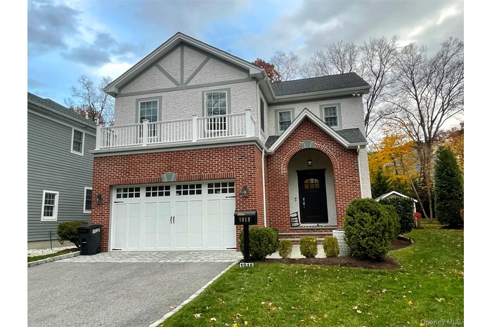 Tudor home with asphalt driveway, brick siding, a front lawn, and an attached garage