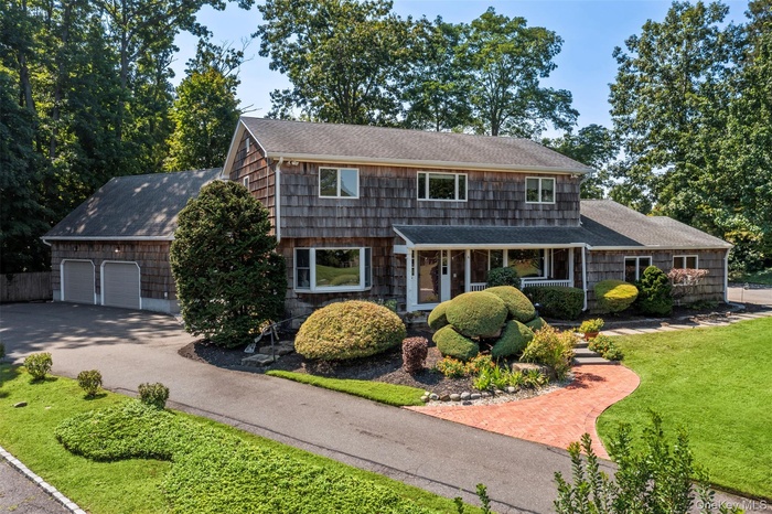 View of front of house with a shingled roof, a front lawn, driveway, and a porch