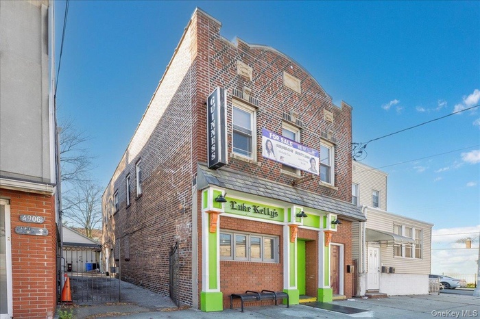 A classic brick mixed-use building featuring a bold storefront entrance with distinctive architectural details. Ideal visibility for businesses with s