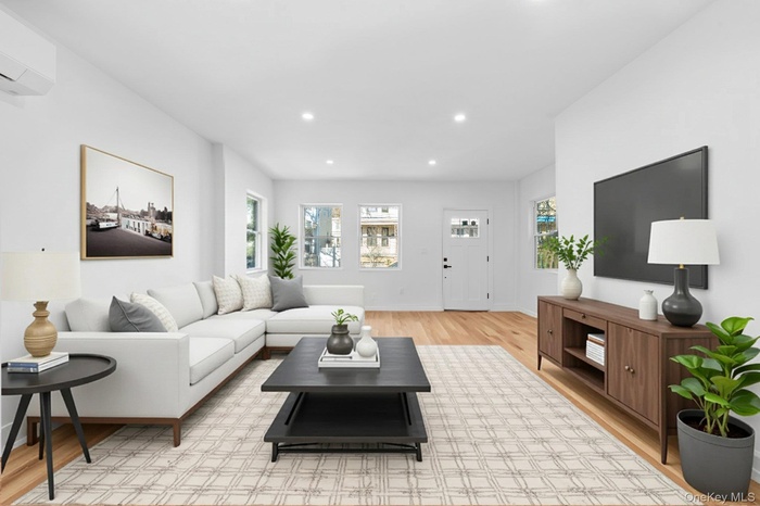 Living room with an AC wall unit, plenty of natural light, recessed lighting, and light wood-type flooring