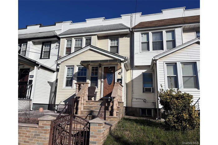 View of front facade featuring a shingled roof and a gate