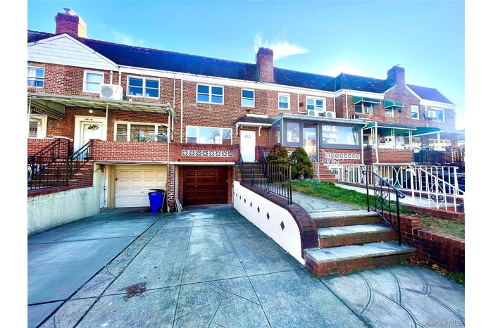 View of front of property with brick siding, stairway, an attached garage, and driveway