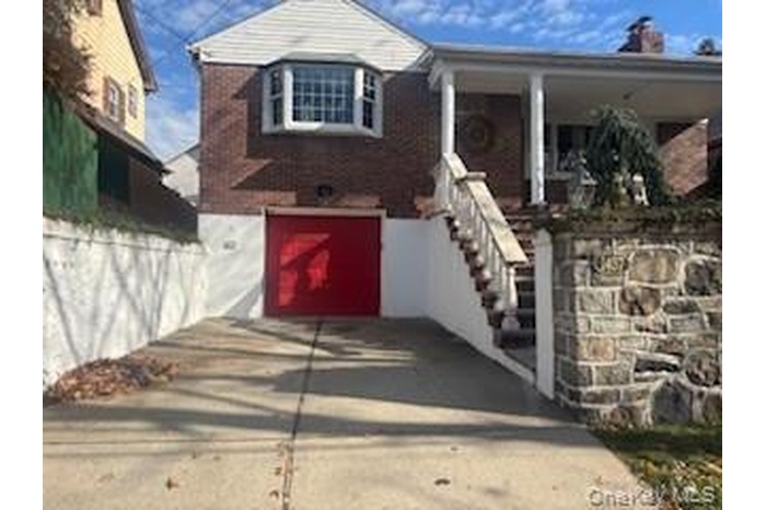 View of front of property featuring driveway, a patio, an attached garage, and stairway