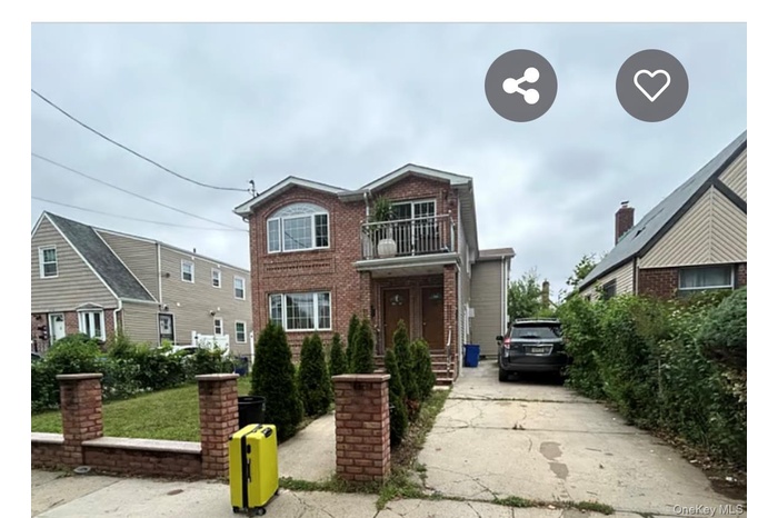 Traditional-style house featuring a balcony, brick siding, and driveway